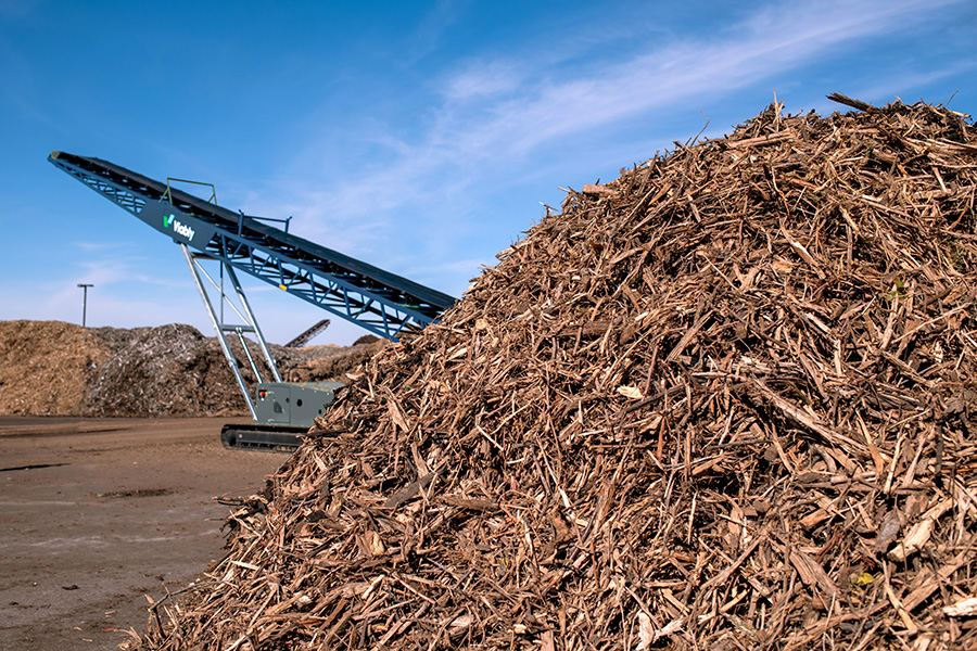 A Viably mobile conveyor behind a bile of mulch.